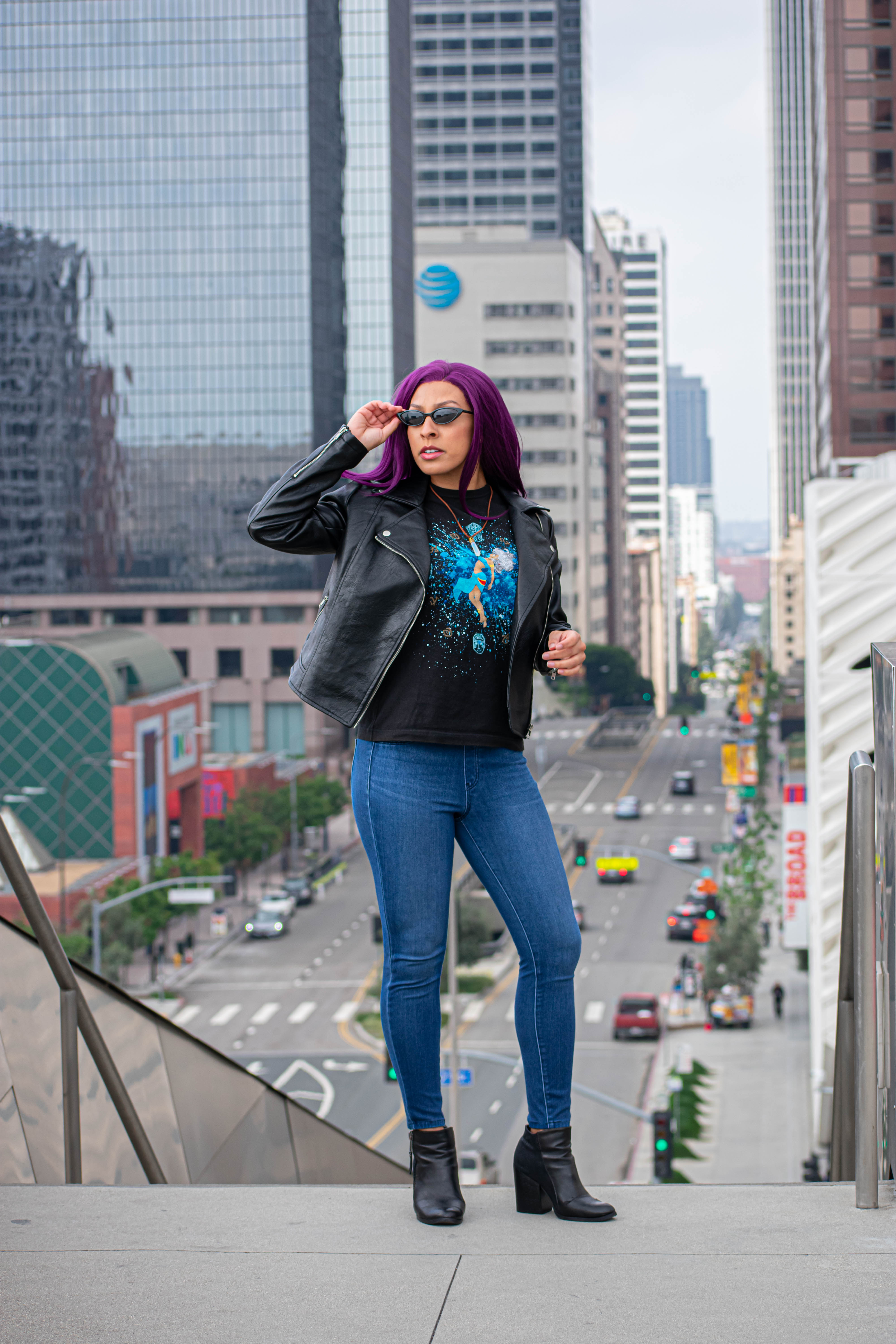 Utahime Cosplay pictured in a Kida inspired Tee Shirt and crystal necklace. She is wearing jeans and a black leather jacket. The Los Angeles Skyline is visible behind her.