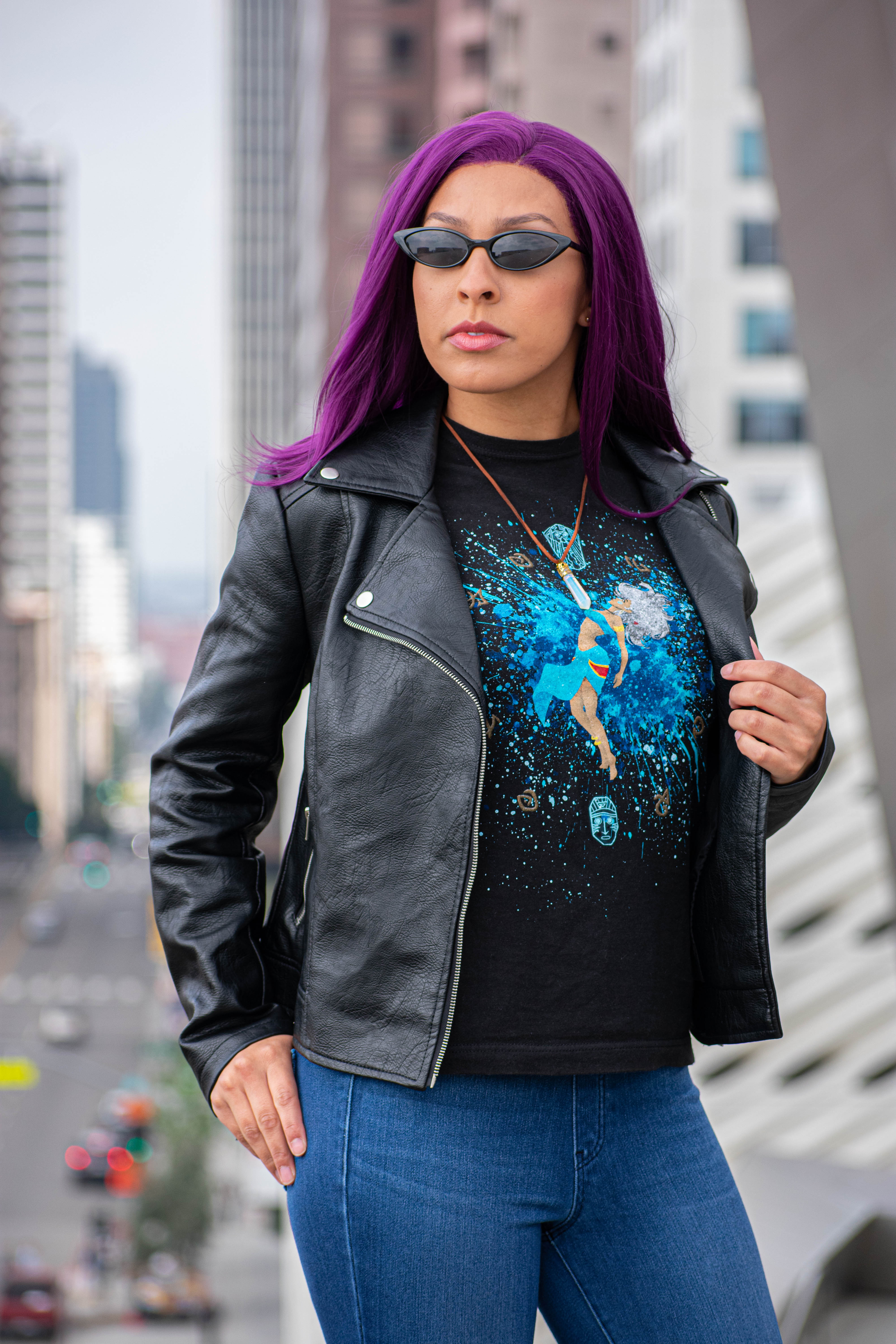 Utahime Cosplay pictured in a Kida inspired Tee Shirt and crystal necklace. She is wearing jeans and a black leather jacket. The Los Angeles Skyline is visible behind her.