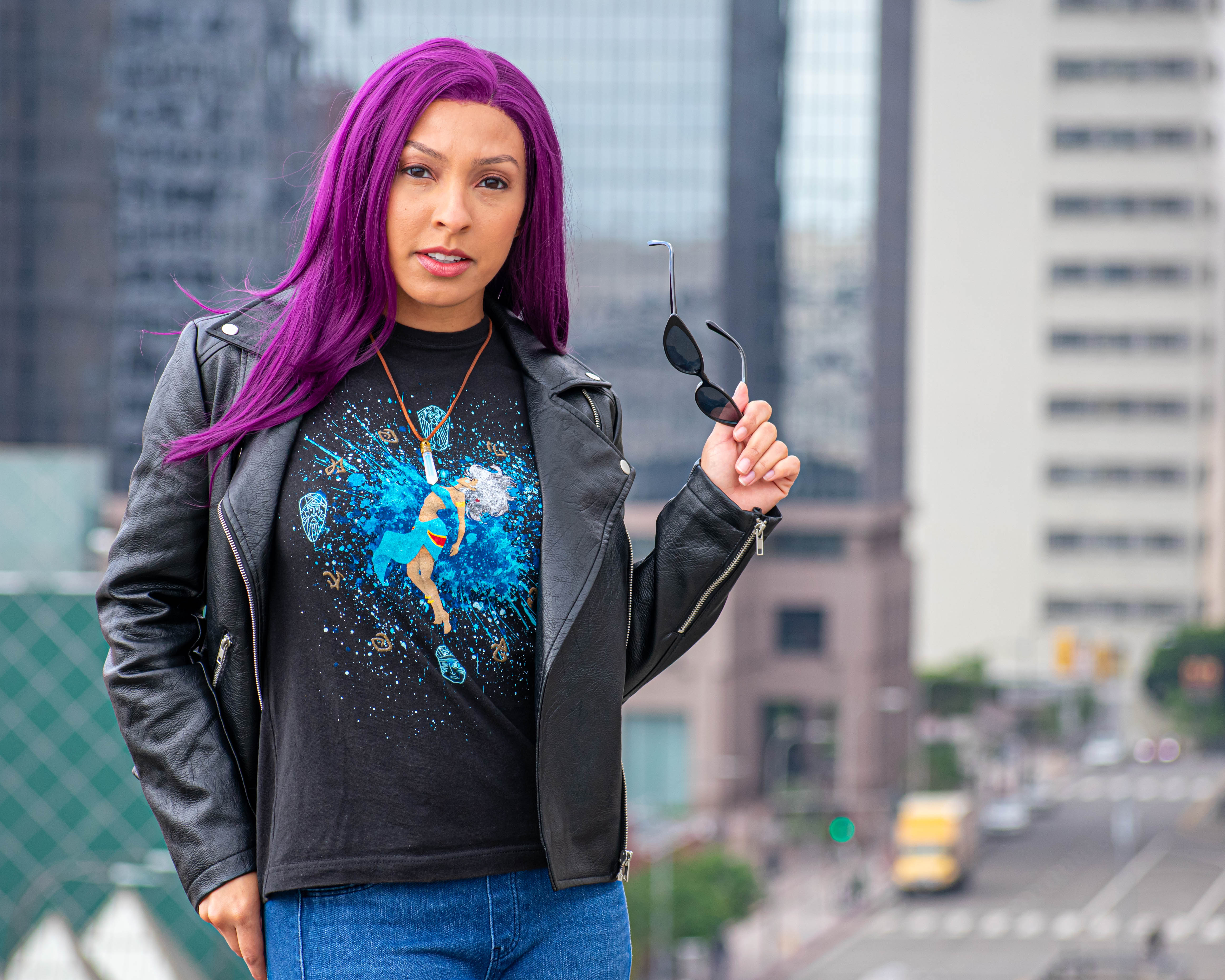 Utahime Cosplay pictured in a Kida inspired Tee Shirt and crystal necklace. She is wearing jeans and a black leather jacket. The Los Angeles Skyline is visible behind her.