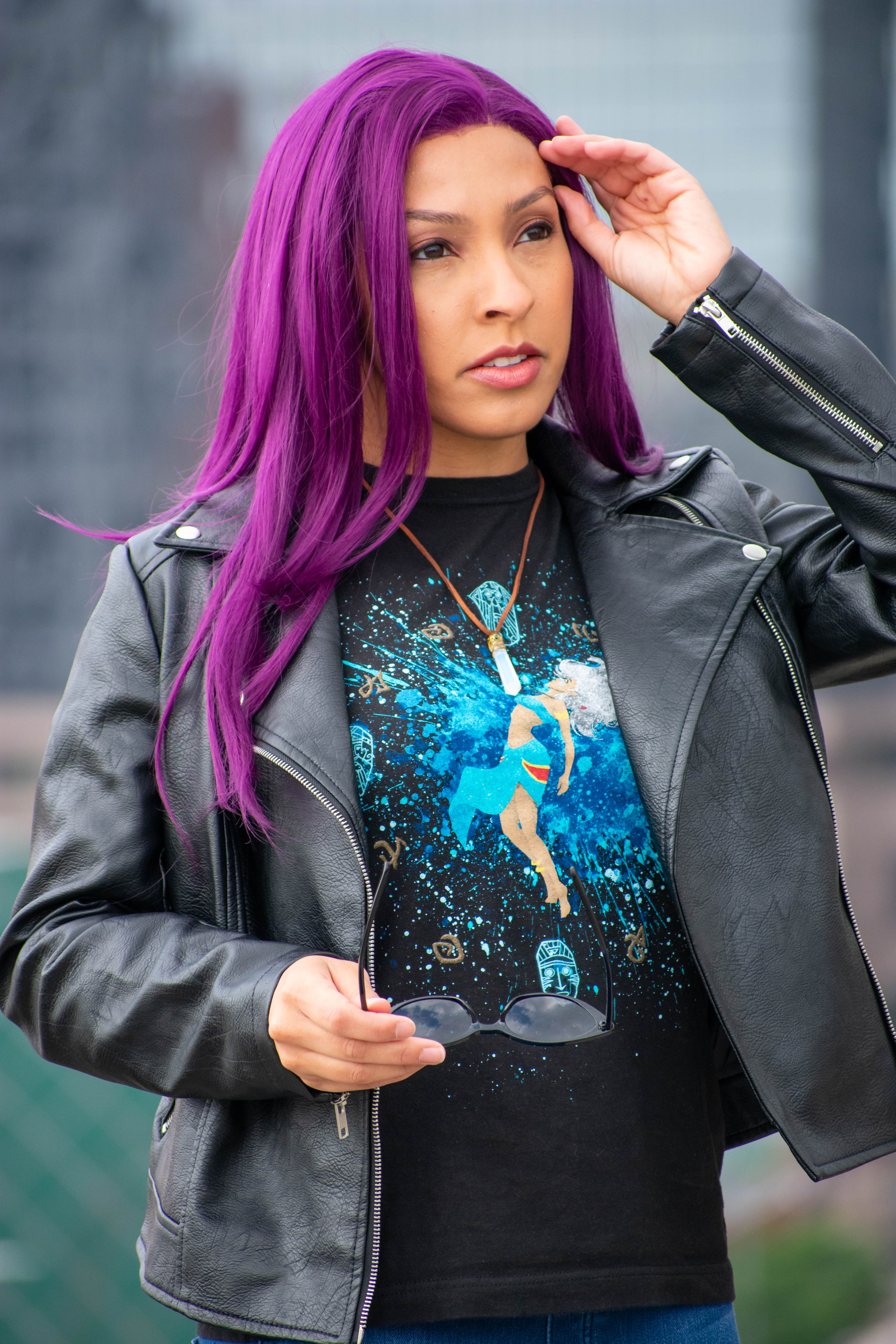 Utahime Cosplay pictured in a Kida inspired Tee Shirt and crystal necklace. She is wearing jeans and a black leather jacket. The Los Angeles Skyline is visible behind her.