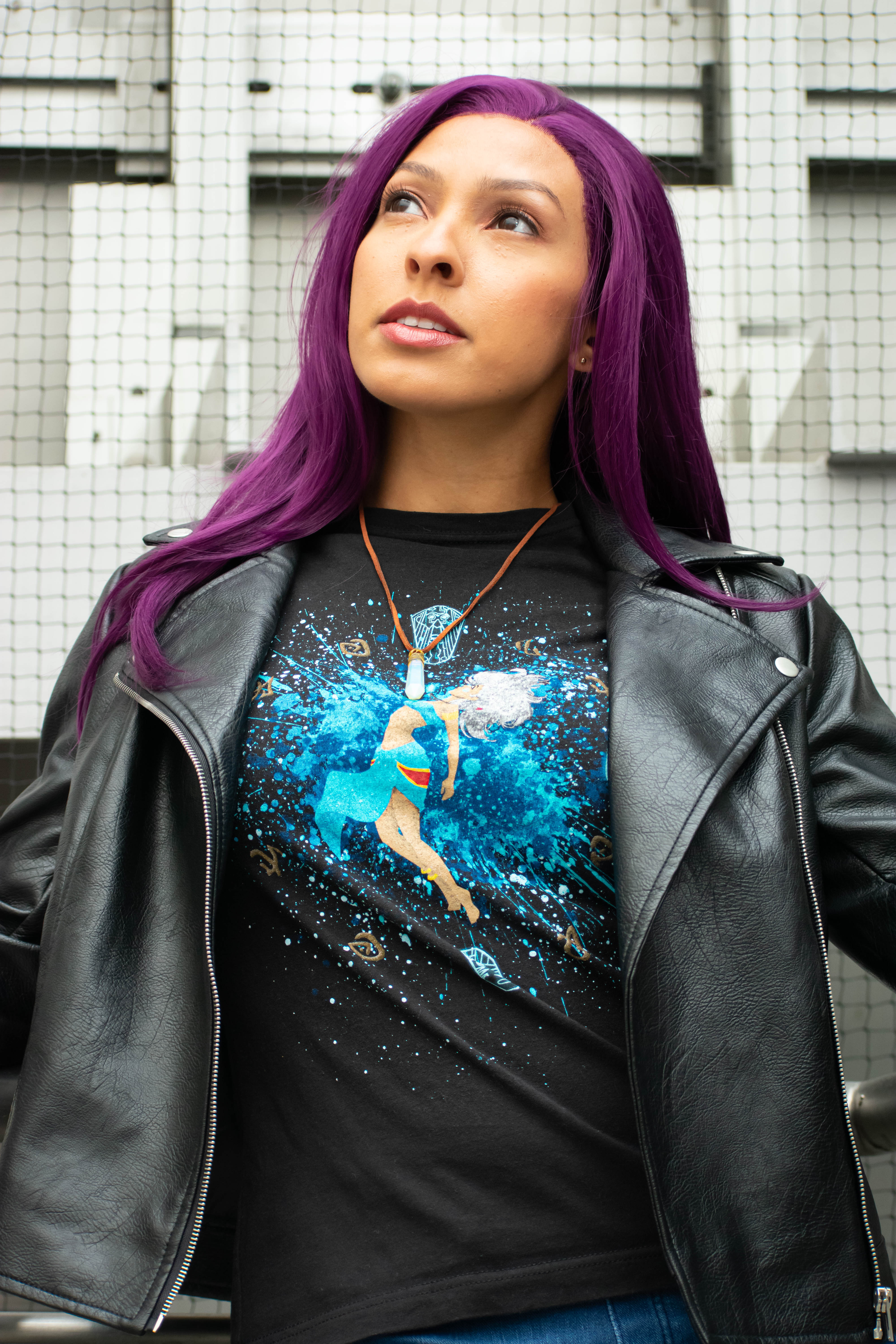 Utahime Cosplay pictured in a Kida inspired Tee Shirt and crystal necklace. She is wearing jeans and a black leather jacket. The Los Angeles Skyline is visible behind her.