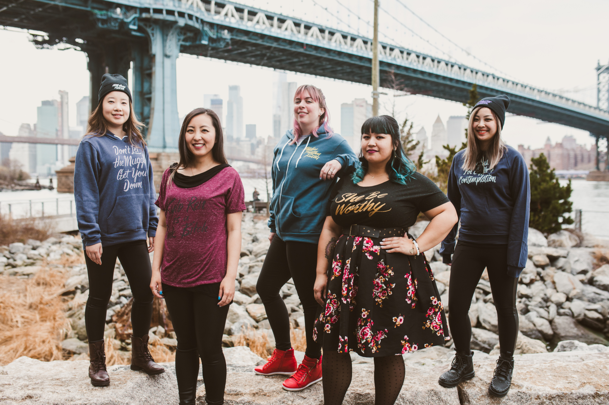 Five women stand below a bridge in New York City wearing Tshirts from Jordan's fashion brand