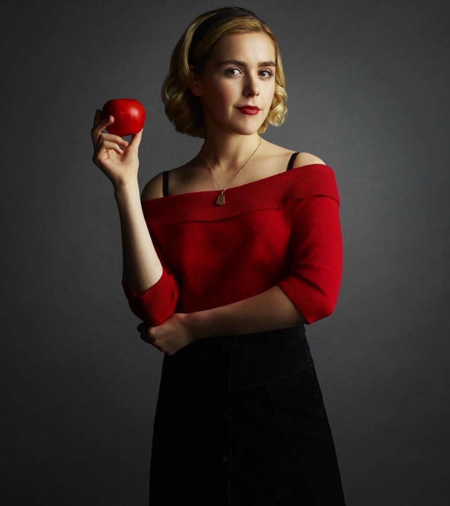 sabrina spellman with a red jumper and apple and necklace