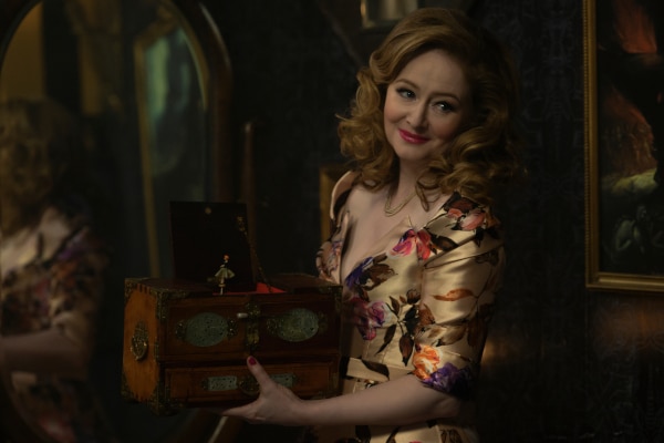 zelda spellman showing her music box, wearing a flattering golden dress, curled her hair