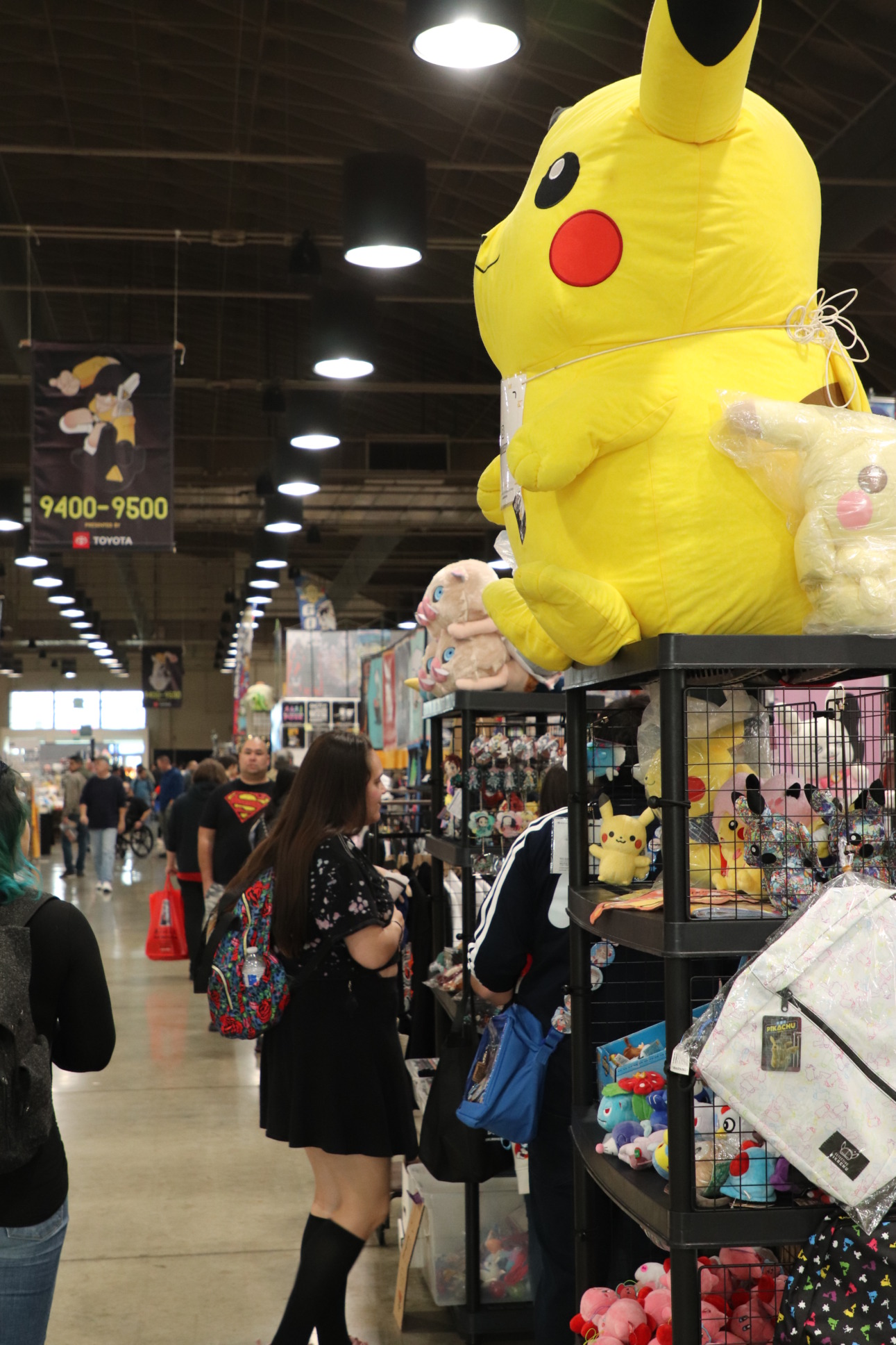 View of an isle of the vendor hall. People are walking around and shopping from booths