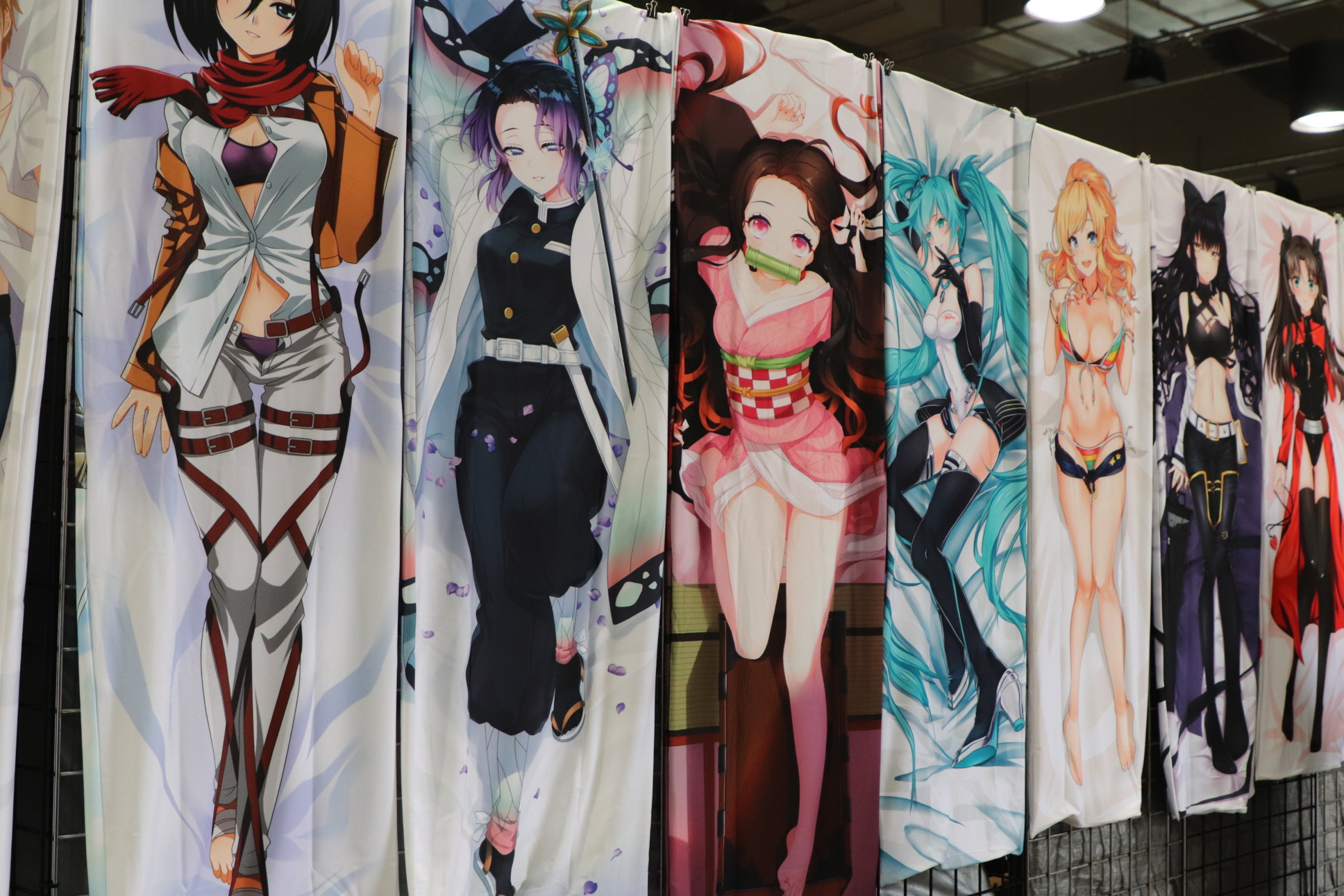 banners of anime characters hang in a vendor booth