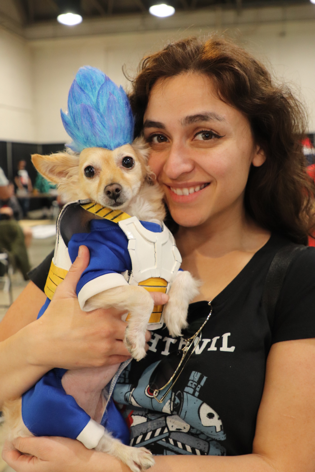 a woman carries a puppy dressed a dragon ball z character