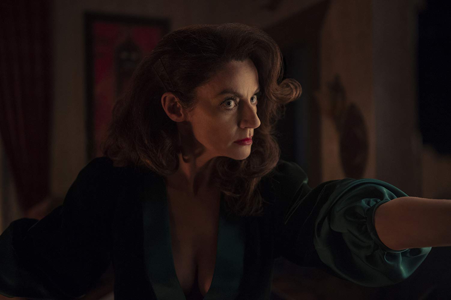 Michelle Gomez in Chilling Adventures of Sabrina (2018). Gomez is dressed in an elegant low cut gown and looks angry. she seems to be pointing at someone.