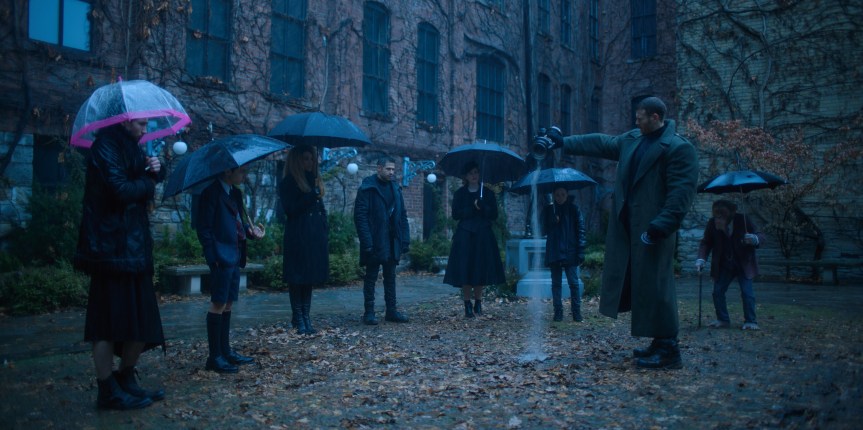 The funeral of Sir Reginald Hargreeves, siblings of the umbrella academy, Mom / robot and Pogo in the backyard of the mansion