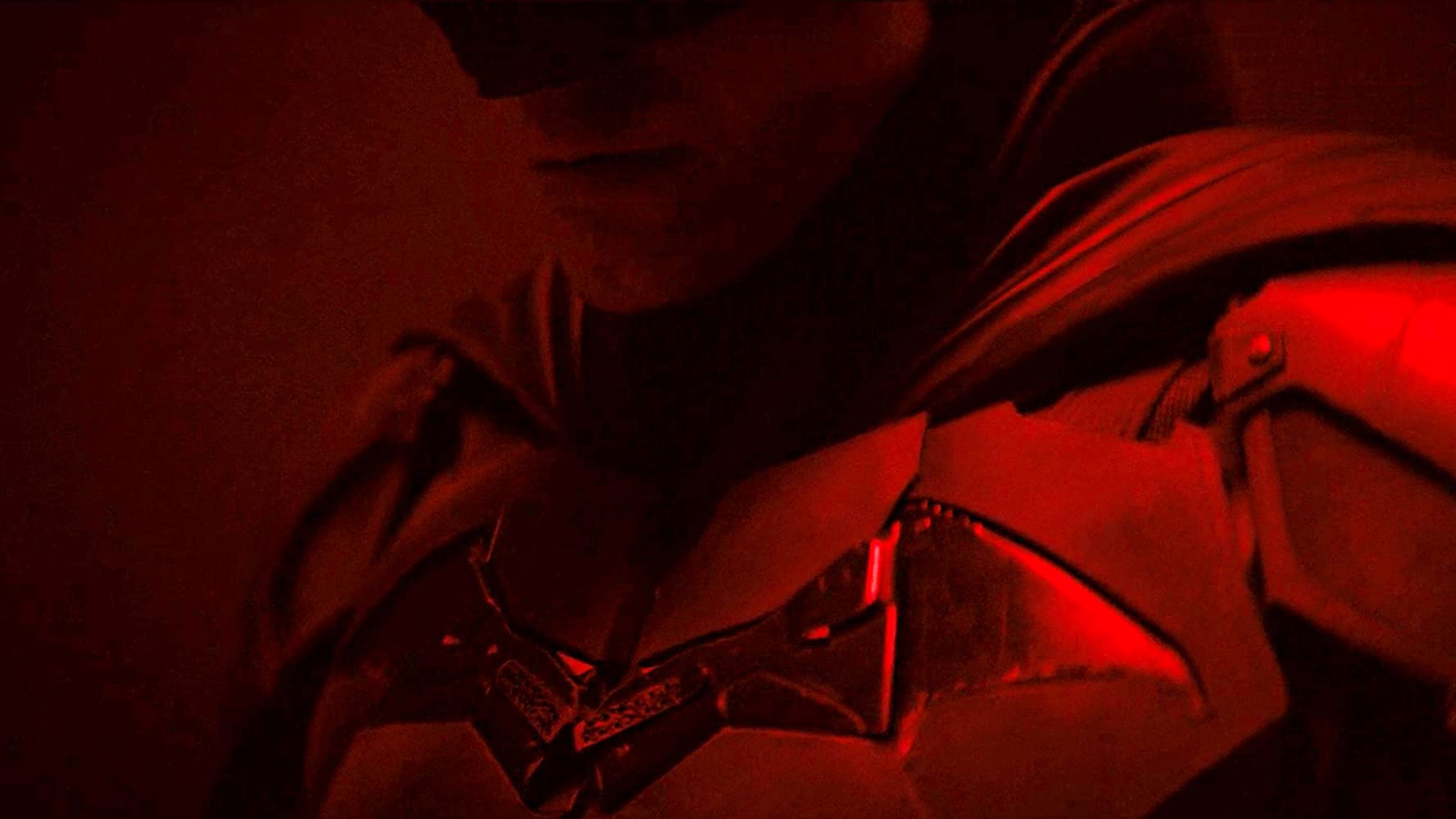 Teaser Image of Robert Pattison as Bruce Wayne / Batman in "The Batman". Image shows Batman in costume from his chin to his torso. The batsymbol is visible on his best. 