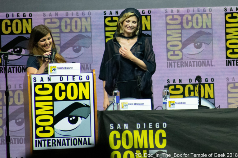 Jodie Whittaker stands on stage and smiles as she's being introduced by Moderator Terri Schwartz and Jodie Whittaker at the "Doctor Who" Panel San Diego Comic-Con 2018