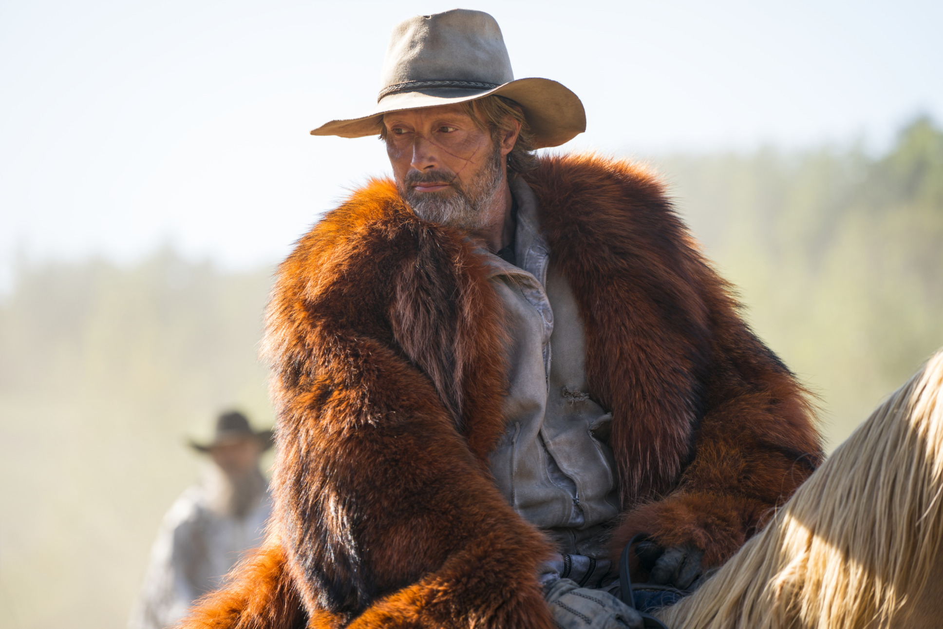 Mads Mikkelsen wearing a fur coat, hat, and riding a horse in Chaos Walking