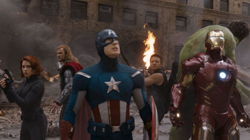 Iron Man, Hulk, Black Widow, Thor, Hawkeye, and Captain America appearing and standing altogether in a battle worn part of New York City