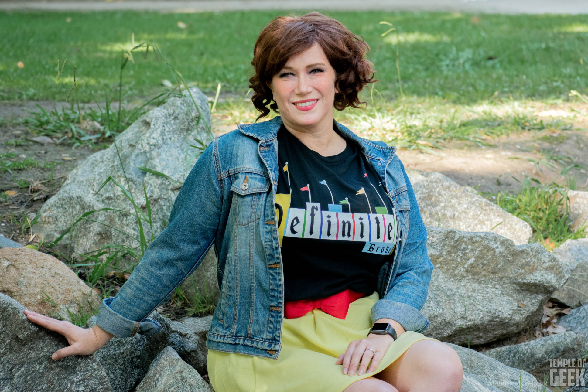 A model sits on a rock, wearing a Disney tee.