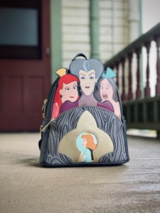 A Cinderella themed Loungefly mini backback features the Evil Stepmother and Stepsisters and Cinderella viewed through a keyhole design. 