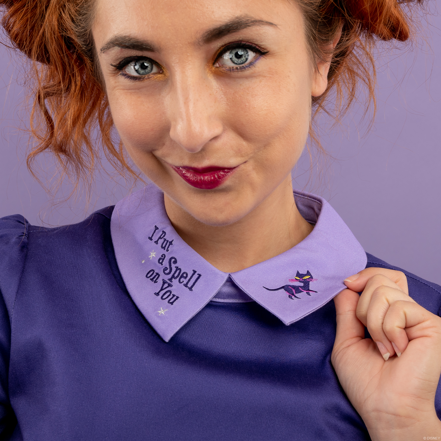 A model tugs at the embroidered collar of a Hocus Pocus dress from the Loungefly Stitch Shoppe brand. It says, "I put a spell on you."