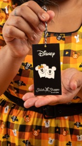 A model holds a Minnie and Mickey Mouse ghost pin from the Loungefly Stitch Shoppe brand. 