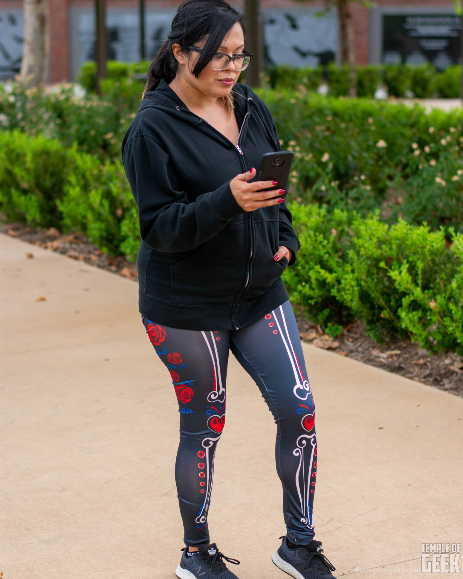 A model looks at her phone while wearing sugar skull leggings from Fun.com.