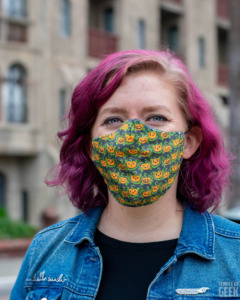 A model wears a Fun.com Halloween face mask with a pumpkin pattern on it. 