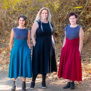 Three models with their hands in their pockets model Longsword dresses. 