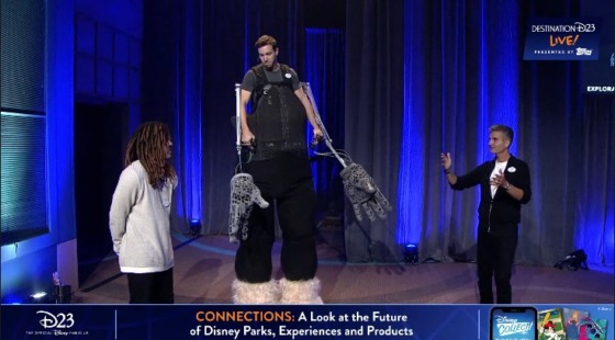 Imagineers show off a new innovation in costuming parks characters- a large exoskeleton which currently features large hands on long sticks attached to and controlled by a cast member, as well as large, oversized feet connected to stilts that the CM is able to walk in