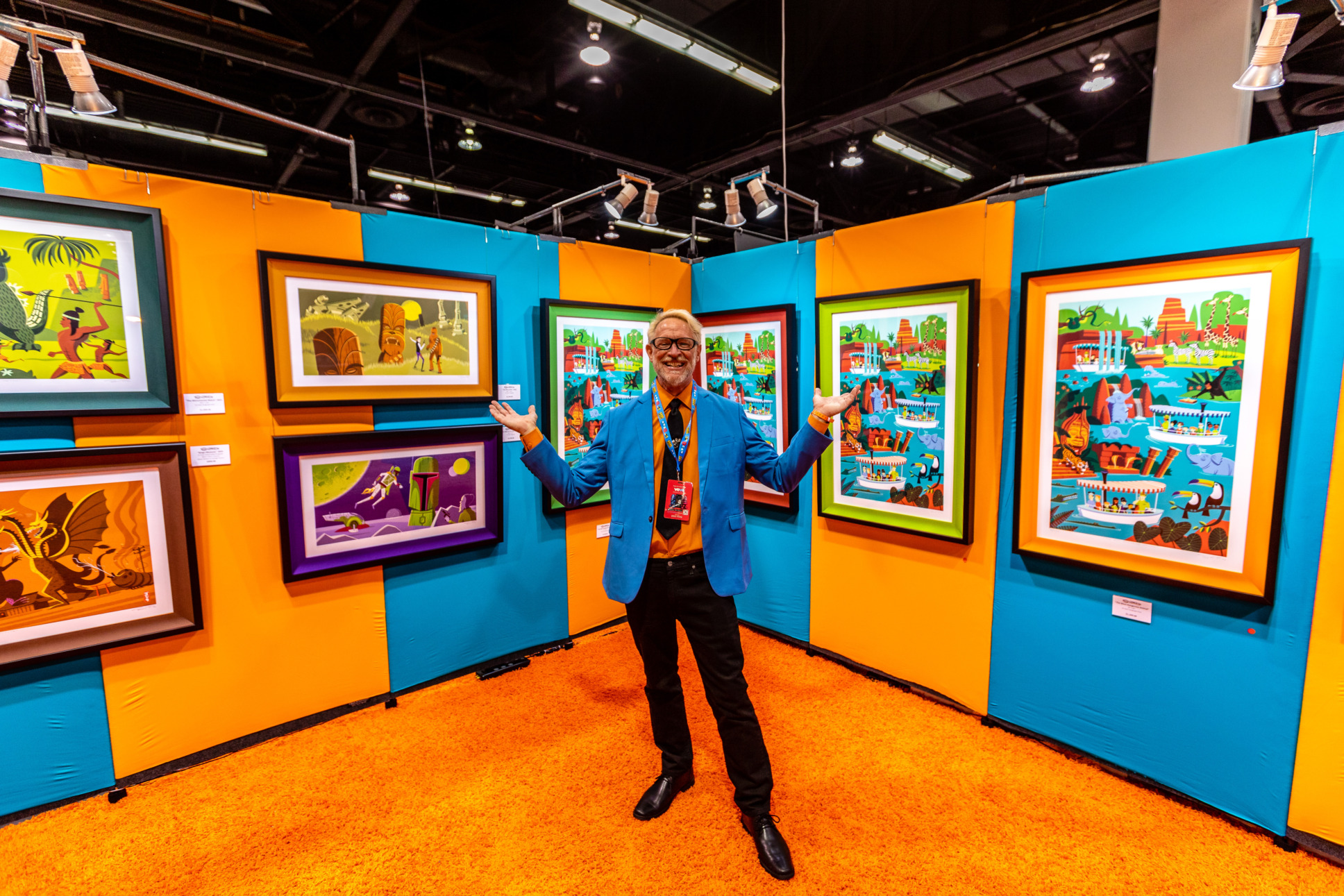 Artist Shag stands in his booth surrounded by his art pieces. 