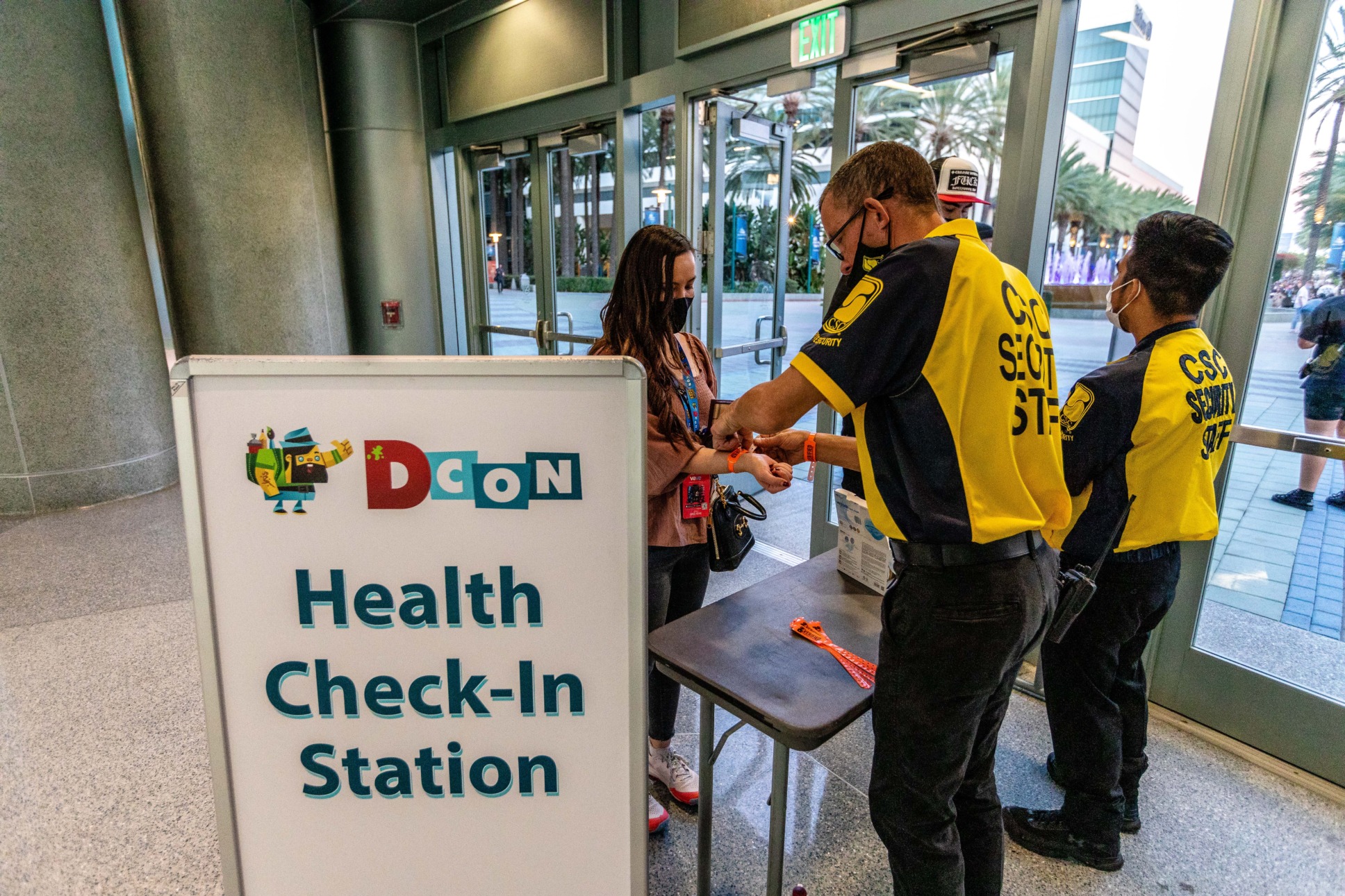 Convention staff place a verified wristband on attendee.