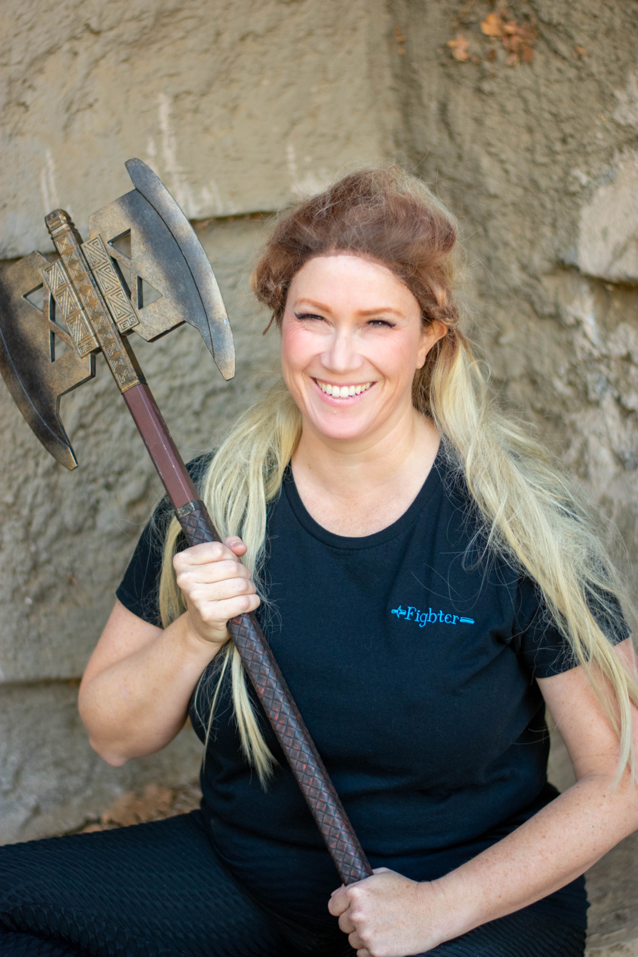 A model smiles and brandishes an axe while wearing a Fighter tee.