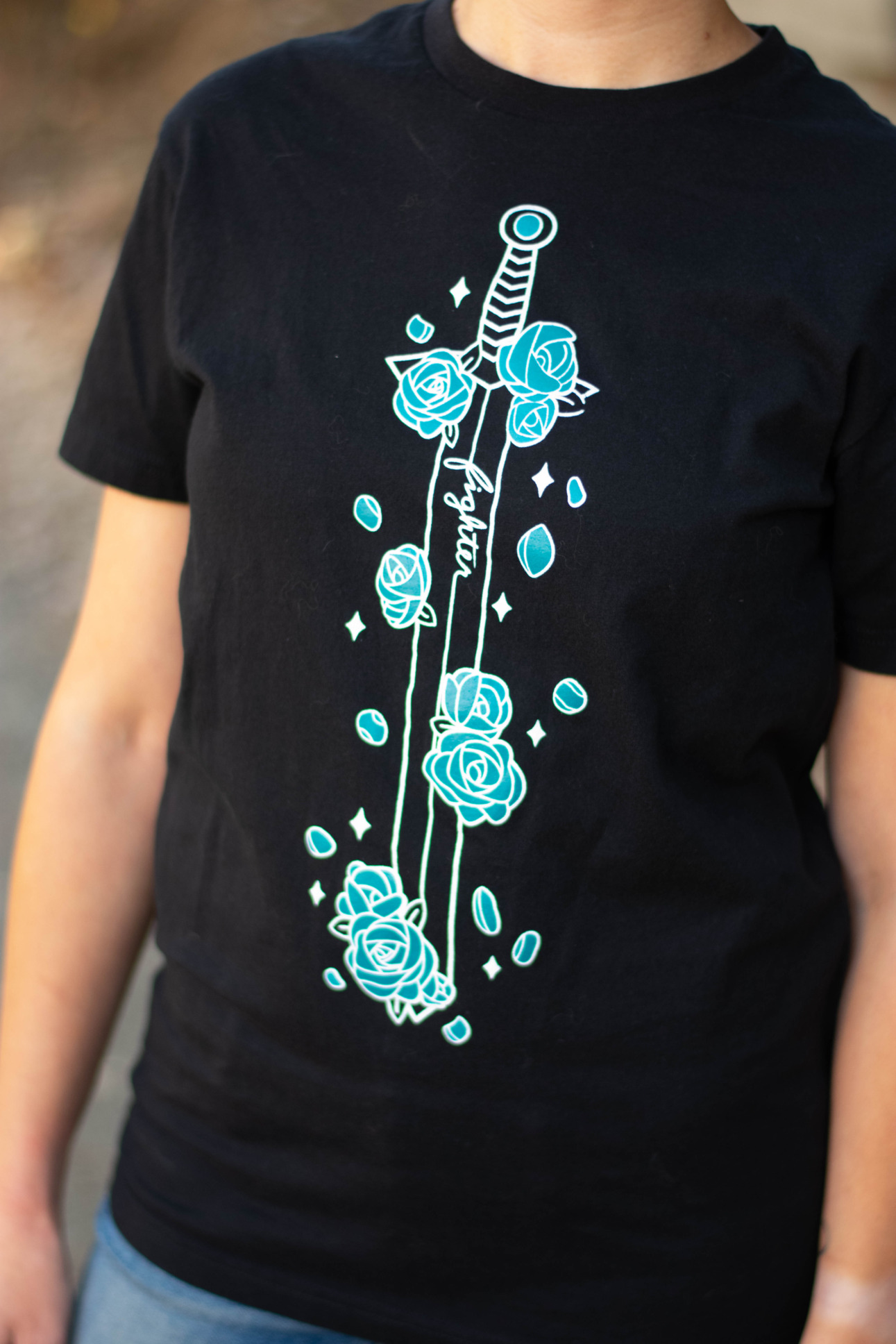 Closeup of a tee featuring a sword covered in blue flowers by D&D fashion brand Guild Party.