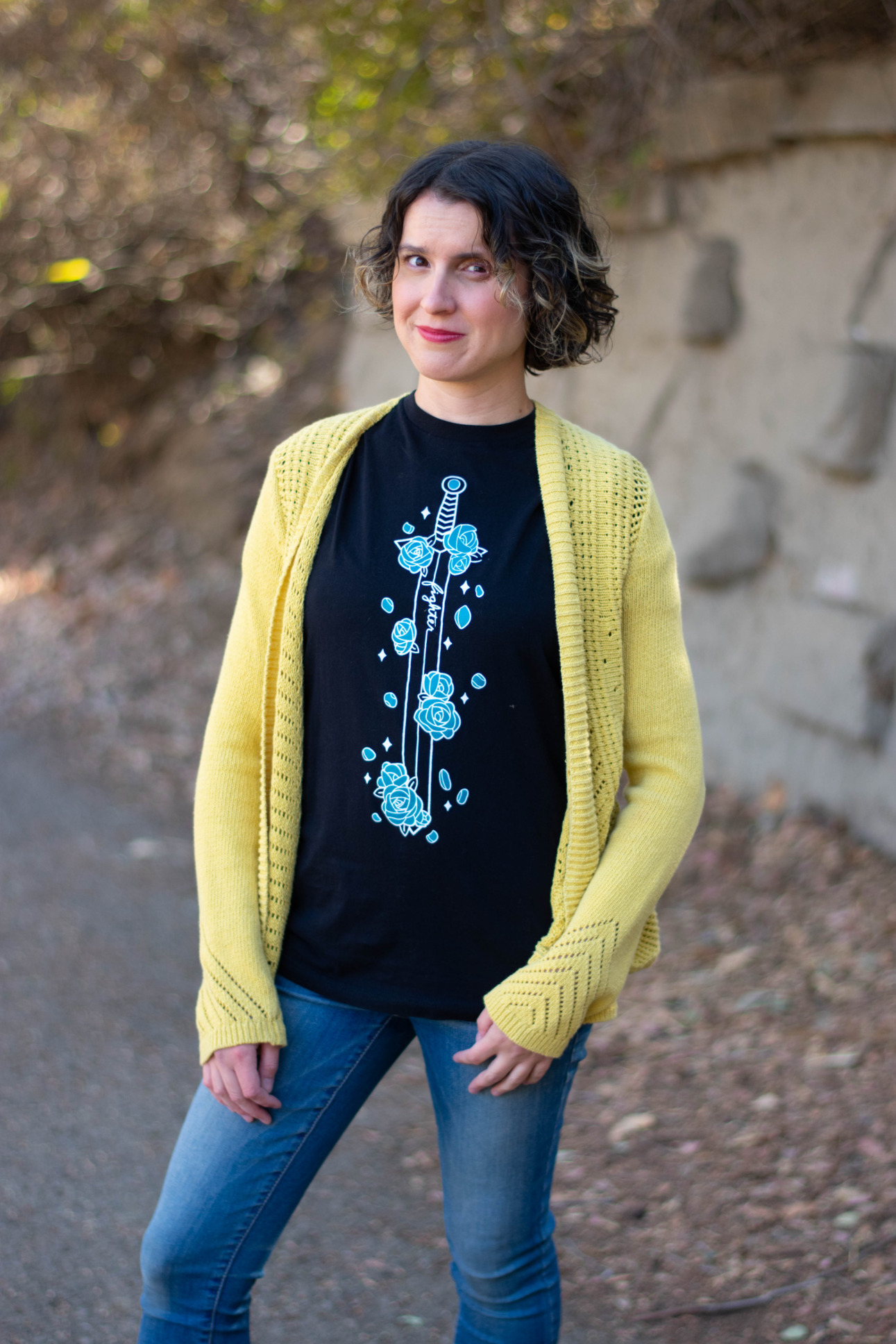 A model wears a yellow cardigan and a tee featuring a sword covered in blue flowers.