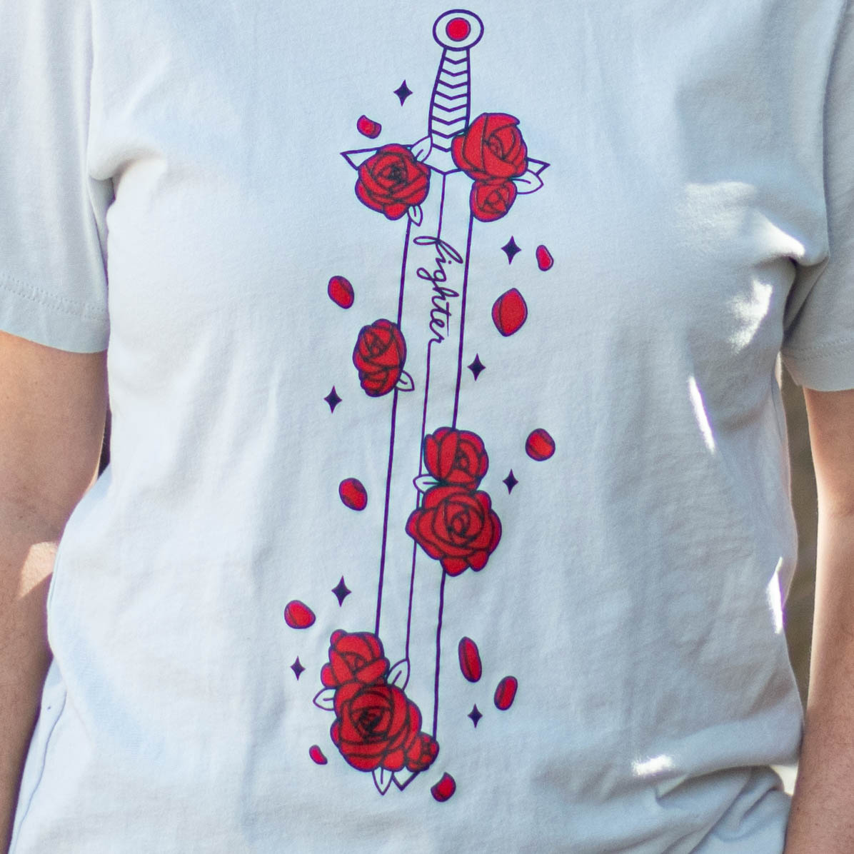 Closeup of a tee featuring a sword covered in red flowers.