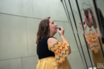 A model applies lipstick using the reflective surface of the Walt Disney Concert Hall. She wears a Captain Marvel-inspired ruffle sleeve top.