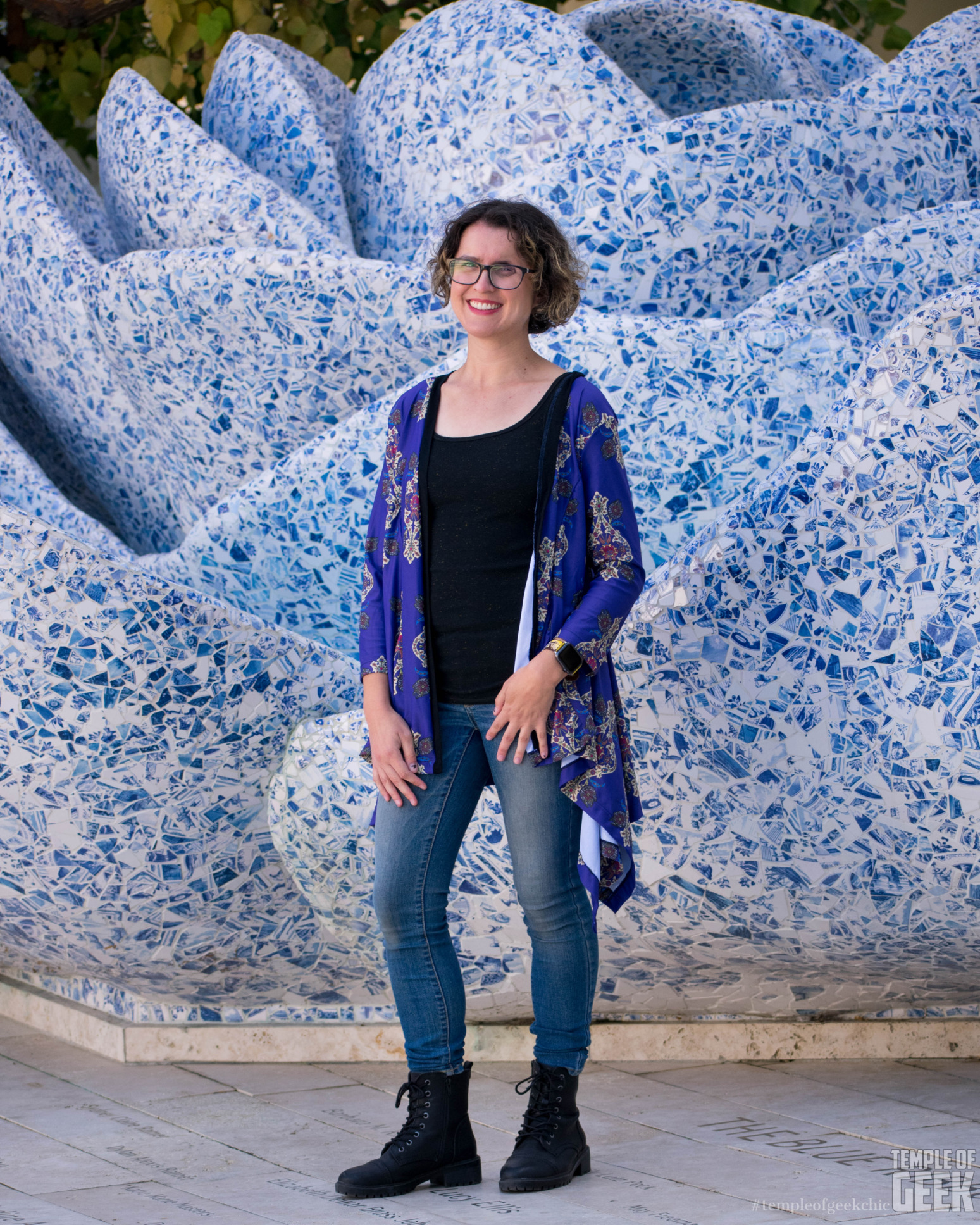 A model wears a purple-blue cardigan in front of the A Rose for Lily fountain at Walt Disney Concert Hall.