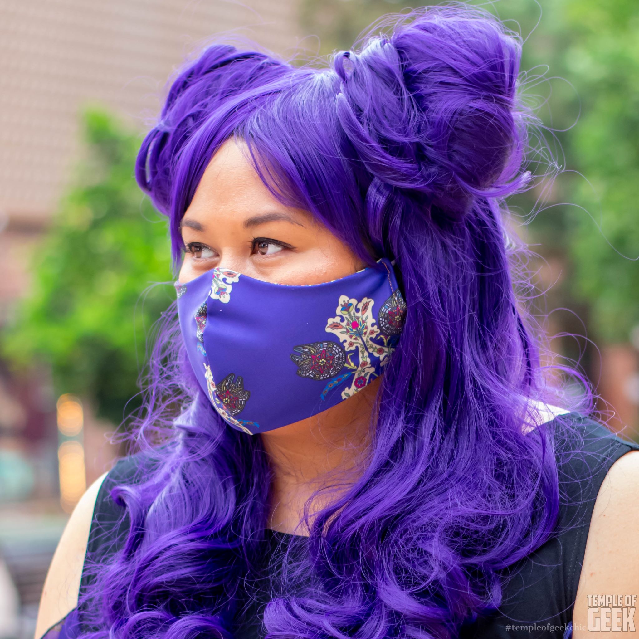 Closeup of a model wearing a purple wig and matching face mask.