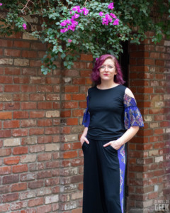 A model stands beneath a flowering vine wearing a Millennium Falcon inspired top and pants by Heroicouture. 