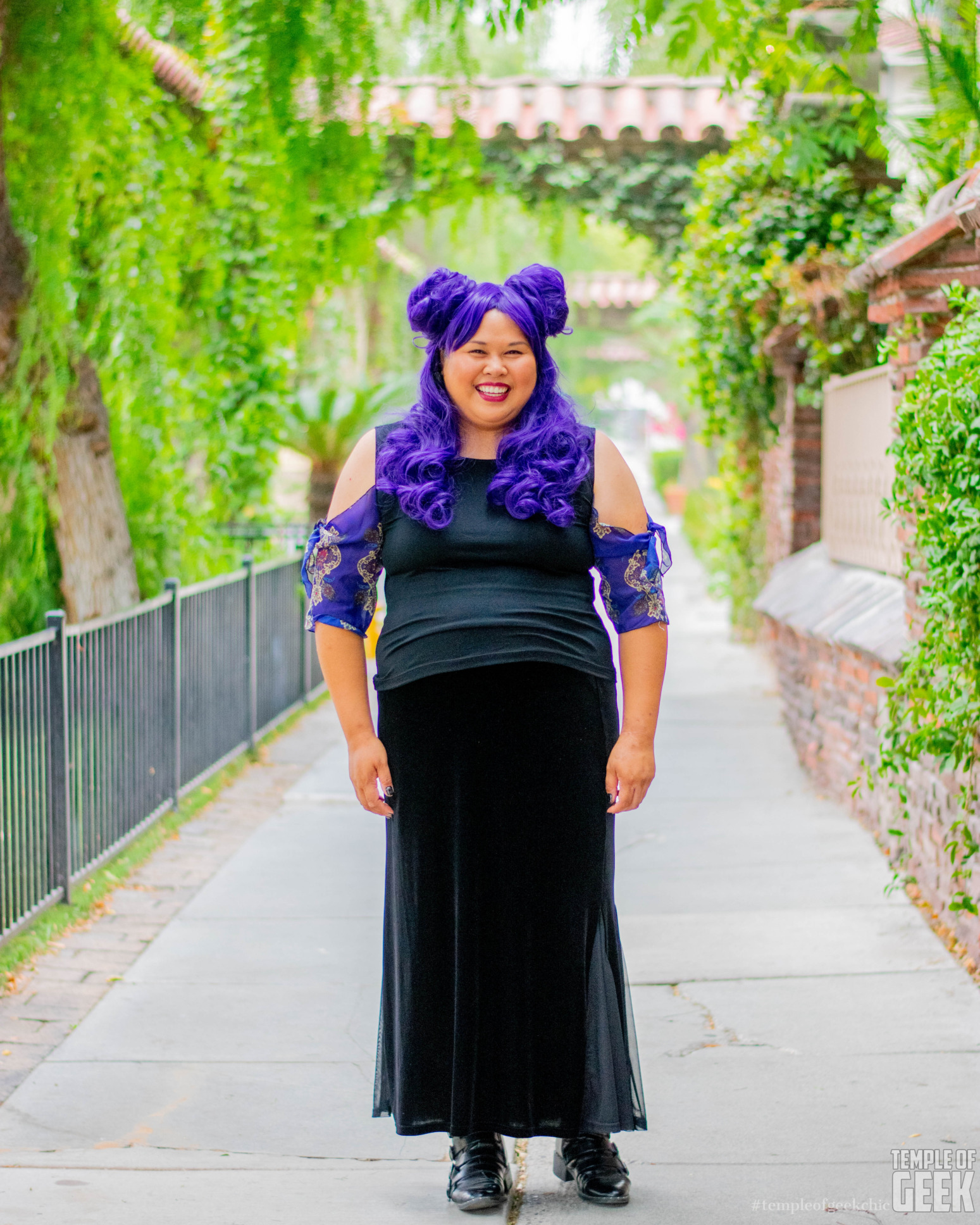 A model wears a top by Heroicouture against a backdrop of vines and foliage.