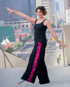 A model does a twirl in front of an LA city view. She wears palazzo pants by Heroicouture. 