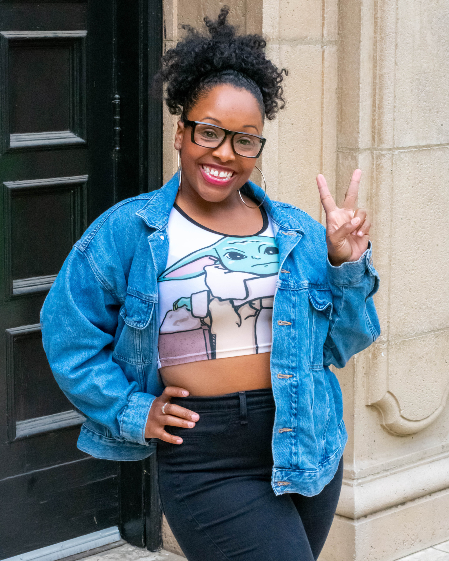 A model wears a crop top with a Star Wars style Grogu illustration with a denim shirt over it.