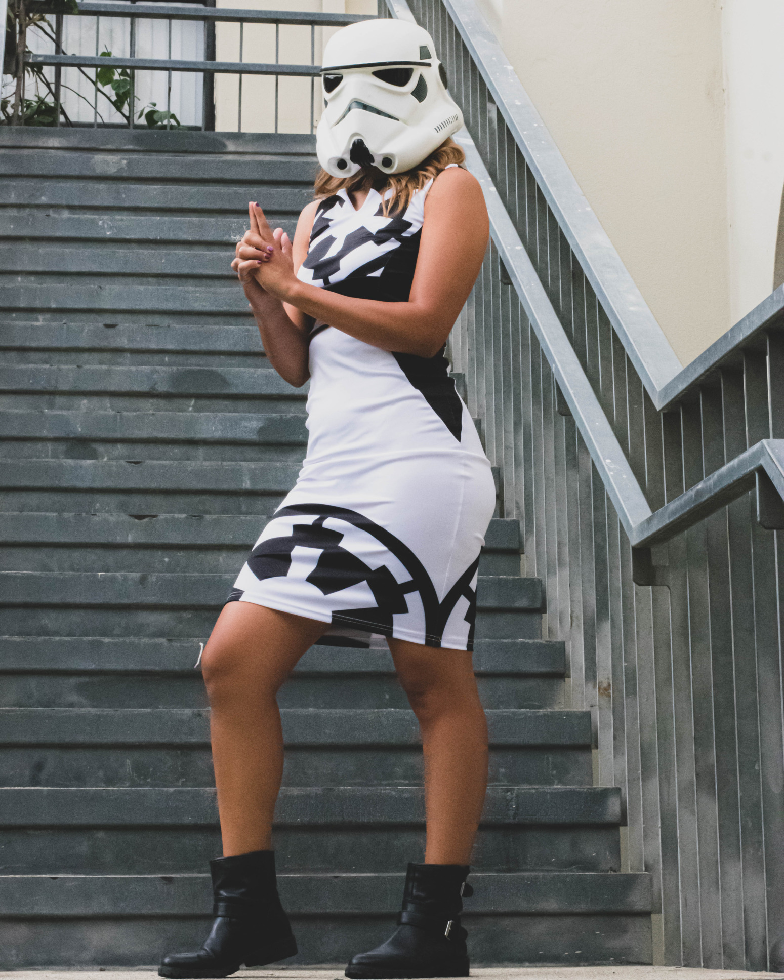 A model wears a Stormtrooper helmet and a dress design inspired by Stormtroopers while mimicking shooting a blaster.