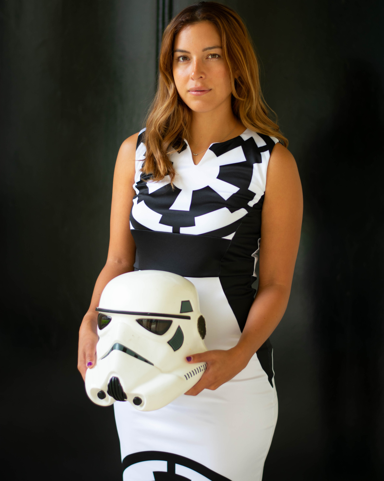 A model holds a Stormtrooper helmet and wears a dress with a Stormtrooper design on it.