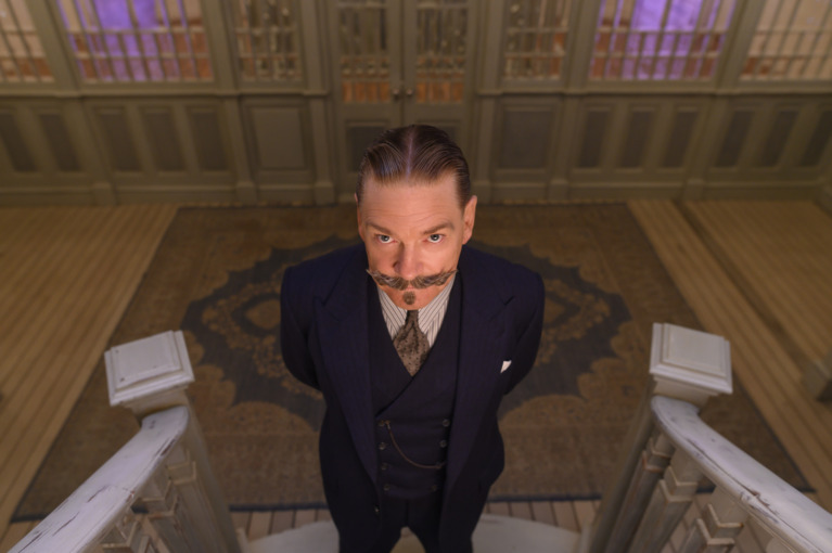 Poirot (Branagh) stands at the end of a staircase