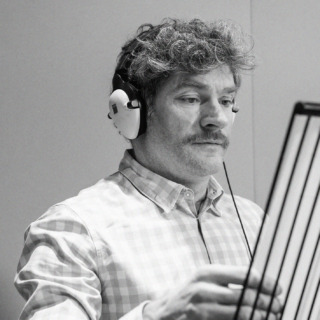 a black and white photo of actor Harry Peacock recording his part for the new audio drama