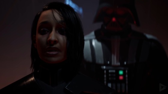 Darth Vader- dressed in his iconic all-black armor and menacing helmet- stands behind Trilla- the unmasked Second Sister