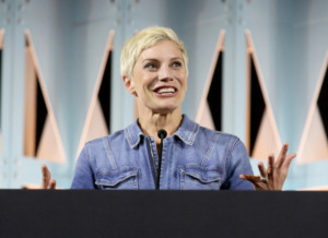 Actress Katee Sackhoff looks to the right while at "The Mandalorian" Panel. She is wearing a blue demin jacket and has short blonde hair