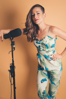 Carolina Ravassa actress and producer of Morgan's Mask standing next to a tall microphone