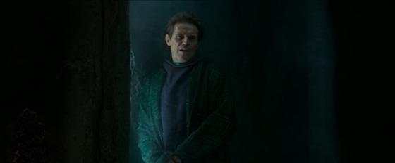 a screenshot of Norman in No Way Home, trapped in one of Dr. Strange's cells, leaning on the wall and wearing a green coat and purple shirt