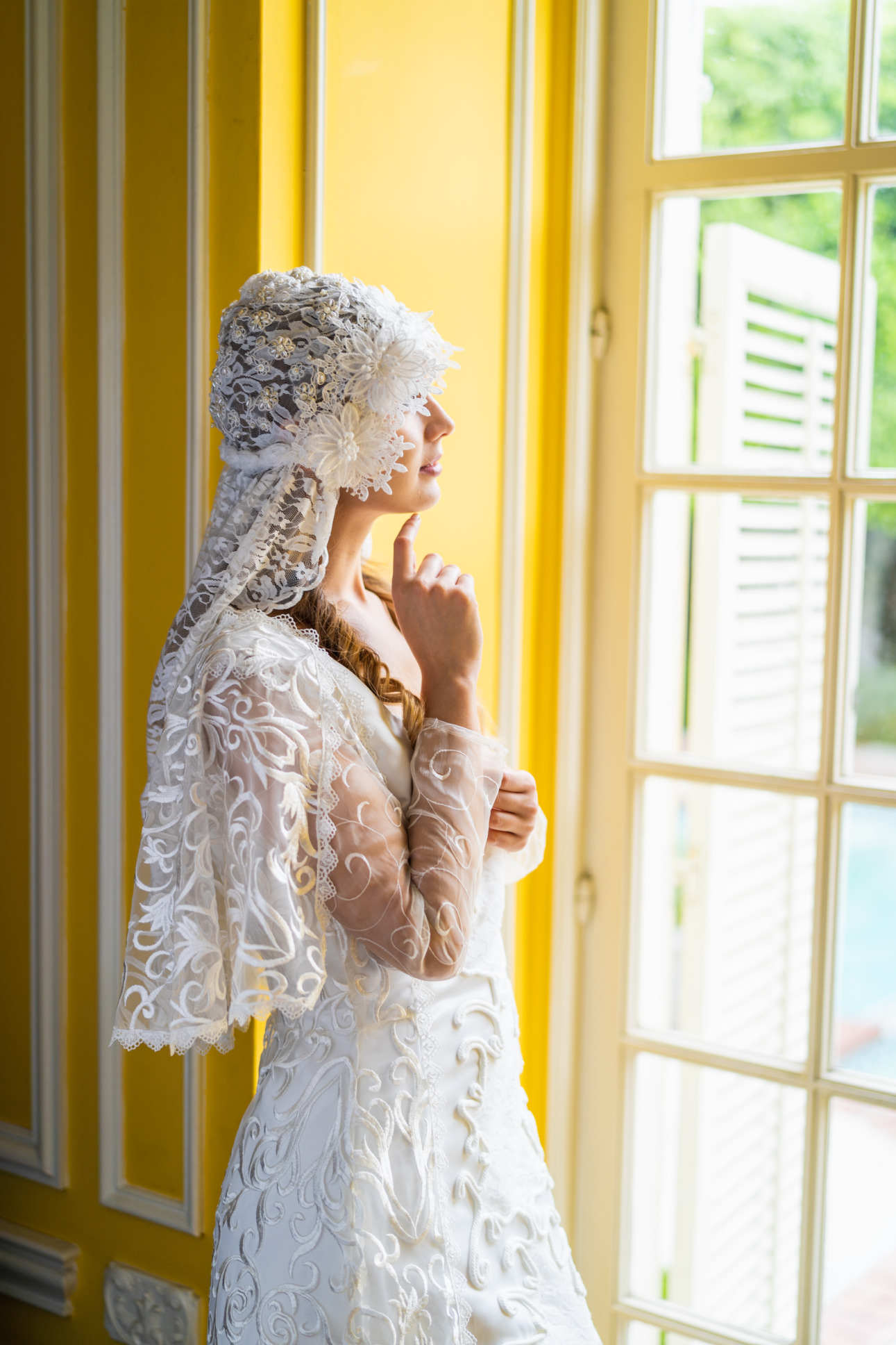 A model looks out a window wearing a lacy white veil and replica of Padme Amidala's wedding dress from Star Wars: Attack of the Clones.