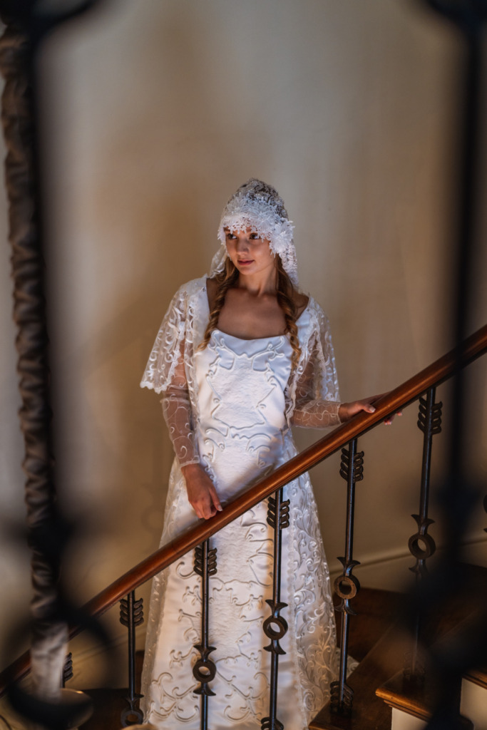 A model stands on a staircase wearing a replica of Padme Amidala's wedding dress and lacy veil from Star Wars: Attack of the Clones. 