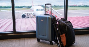 Luggage sits at the window of an airport with a plane in the background