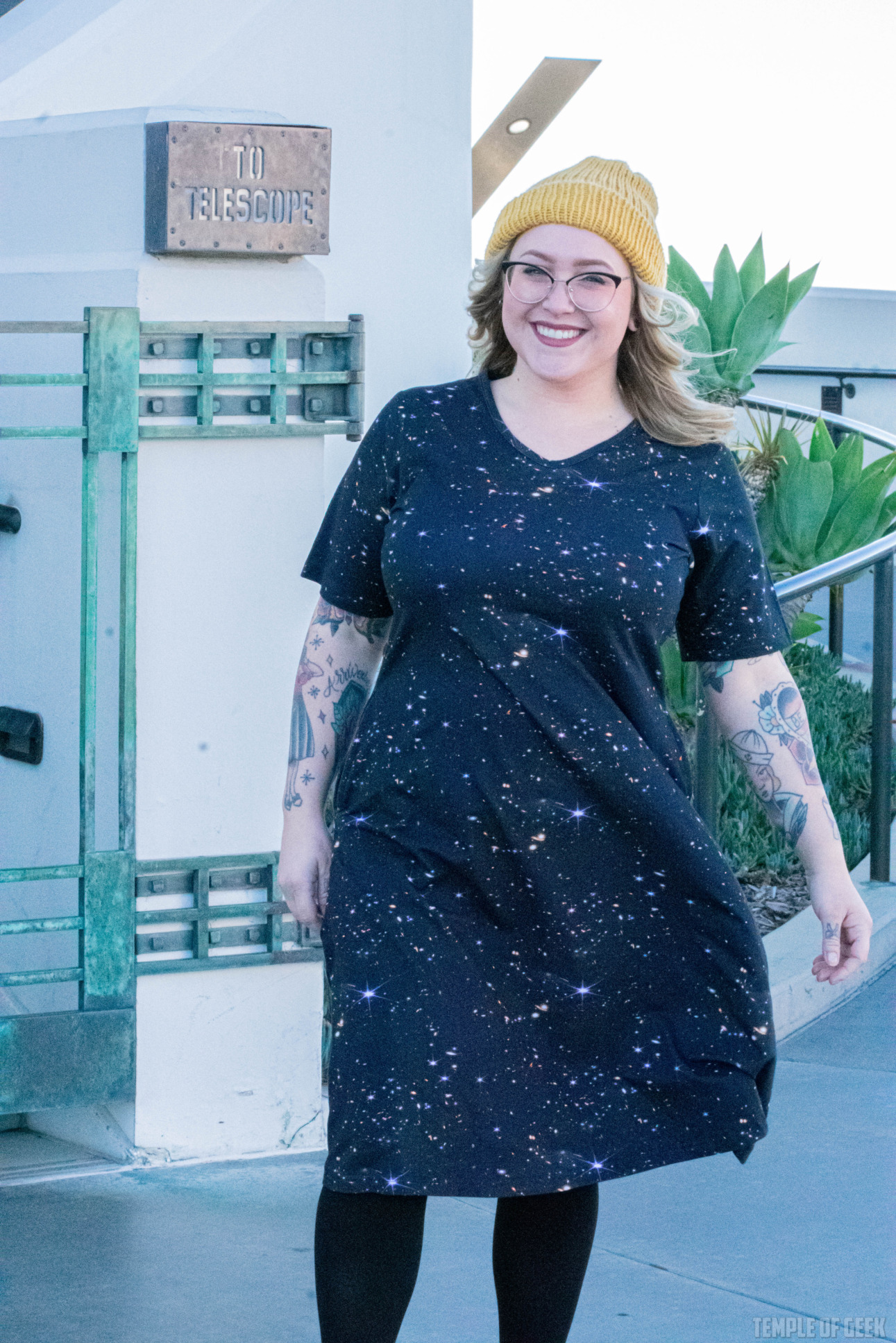 A model wears a fit and flare dress with a black background and starbursts on it outside Griffith Observatory.